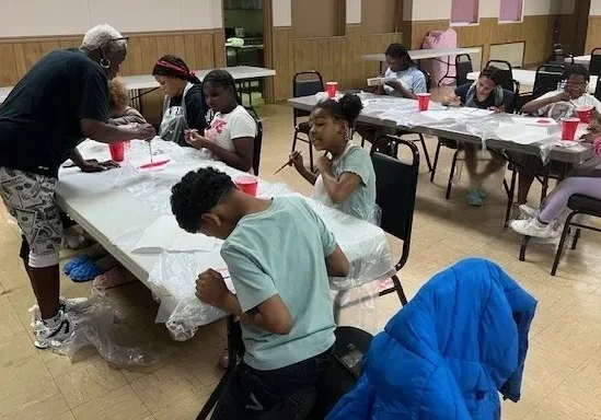 Children painting at tables in a classroom.